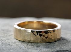 a gold wedding ring sitting on top of a rock