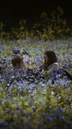 two people sitting in a field of flowers