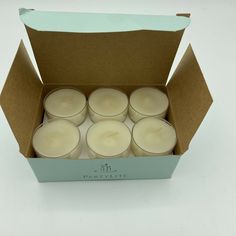 six candles in a cardboard box on a white surface