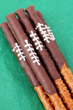 four chocolate sticks with white frosting on them sitting on a green tableclothed surface