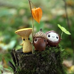 three little figurines sitting on top of a tree stump in the woods next to a flower