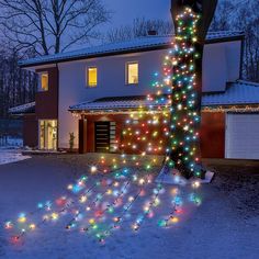 a house is decorated with christmas lights in the front yard and trees are lit up