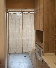 an empty kitchen with wooden cabinets and white counter tops is seen in this image from the doorway