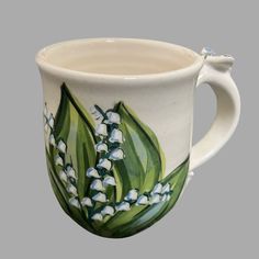 a ceramic mug with lily of the valley flowers painted on it's outside rim