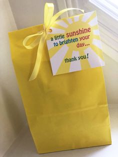 a yellow paper bag with a note attached to the handle that says, a little sunshine is to brighten your day thank you