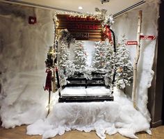 a room decorated for christmas with fake trees and snow on the floor, including a bench