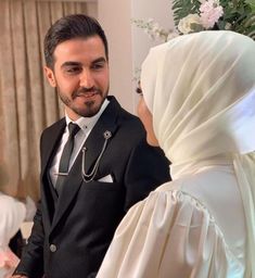 a man in a tuxedo standing next to a woman wearing a white shawl