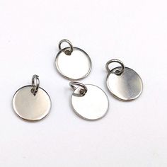 four different sized metal charms on a white surface