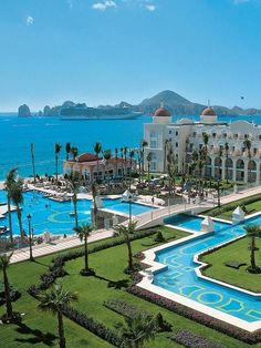 an aerial view of a resort with a pool and palm trees in the foreground