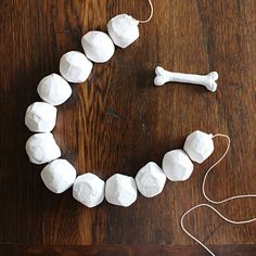 a wooden table topped with white marshmallows and a dog bone shaped necklace