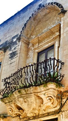 an old building with wrought iron balconies and plants growing out of the balcony