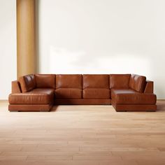 a brown leather couch sitting on top of a hard wood floor next to a white wall