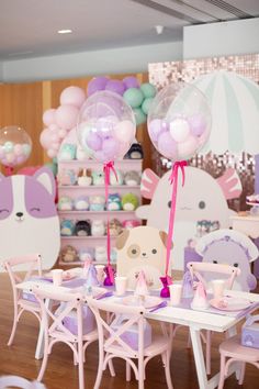 there are balloons and other decorations on the tables at this birthday party with pink chairs