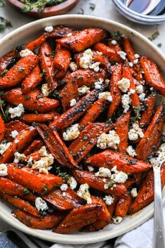 roasted carrots with feta cheese and herbs in a white bowl on a table