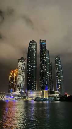 some very tall buildings by the water at night