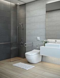 a white toilet sitting next to a bath tub in a bathroom on top of a hard wood floor