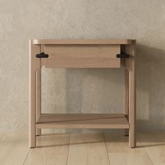 a wooden table with two black handles on the top and one shelf below it, against a beige wall