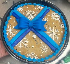 a cookie cake with blue ribbon and snowflakes on it