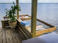 a wooden dock with two chairs and a potted plant on the deck next to it