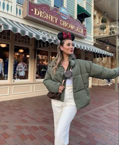 a woman is standing in front of a disney store wearing a mickey mouse ears hat