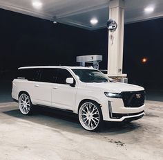 a white suv is parked in front of a gas station with its lights on at night