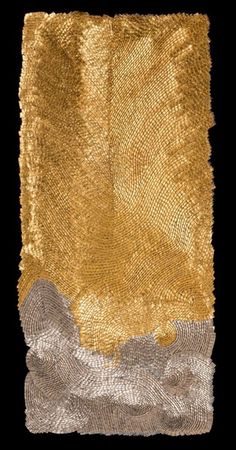 a piece of cloth with gold and silver sequins on it, against a black background