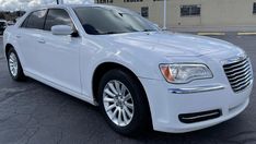 a white chrysler limo is parked in front of a business building with the door open