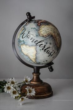 a small globe with the words welcome home written on it and some flowers around it