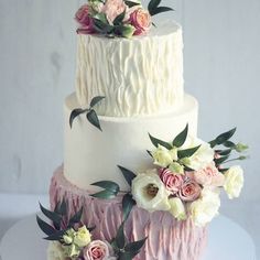 a three tiered cake with pink and white flowers on the top, along with greenery