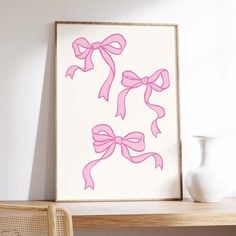 a pink bow is hanging on the wall next to a white vase and wooden shelf