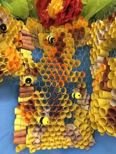 the bees are made out of rolled up paper tubes and some flowers in front of them