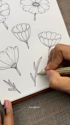 a woman is drawing flowers on a piece of paper with crayon pencils