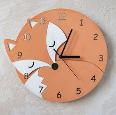 an orange clock with a white face and black numbers on the face is decorated with a fox's tail