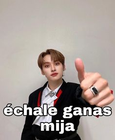 a person giving the thumbs up sign in front of a white wall with text that reads echale ganas mija