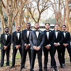 a group of men standing next to each other wearing tuxedos