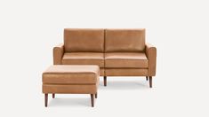 a brown leather couch and footstool sitting next to each other