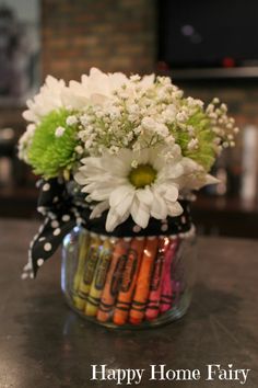 a vase filled with flowers and crayons on top of a table