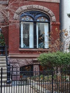 a red brick building with black wrought iron fence and stairs leading up to the front door