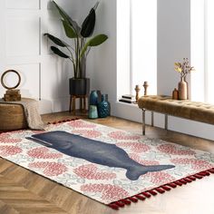 a rug with a whale on it in the middle of a room next to a bench and potted plant