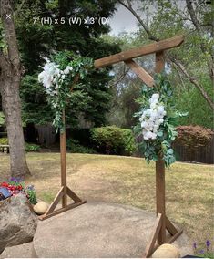 two wooden crosses with flowers on them in front of a tree and grass yard area