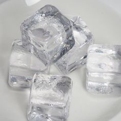 four ice cubes sitting on top of a white plate