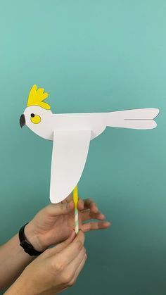 a paper bird is being held by someone's hand with a toothpick