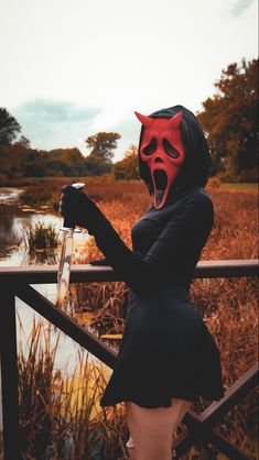 a woman wearing a devil mask and black dress