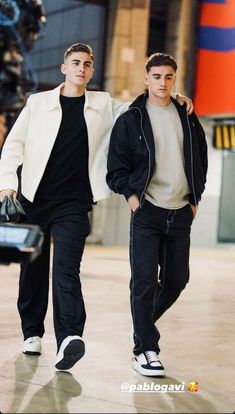 two young men are walking together in an airport