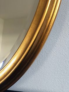 a gold framed mirror sitting on top of a white wall