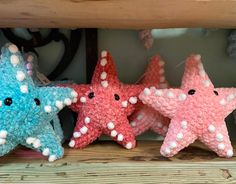 three knitted starfishs sitting on top of a wooden shelf