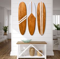 three wooden surfboards mounted to the wall above a white table in a living room