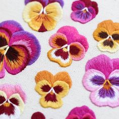 many different colored flowers on a white surface