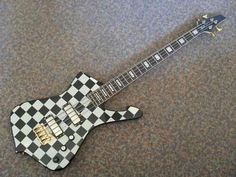 a black and white checkerboard guitar laying on the ground with its neck missing