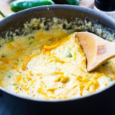 a wooden spoon in a pot filled with cheese